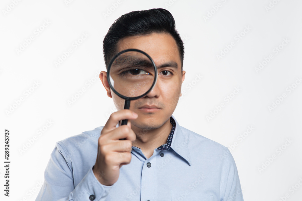 Asian man looking into a magnifying glass. Asian man looking into a magnifying glass.