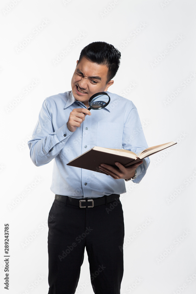 Asian man reading book using a magnifying glass. Asian man reading book using a magnifying glass.