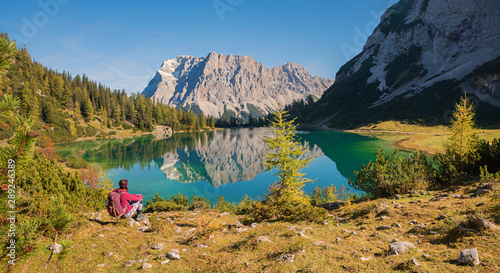 Obraz na płótnie Junge Frau mit Rucksack bewundert das Zugspitz Panorama mit der Spiegelung im Se