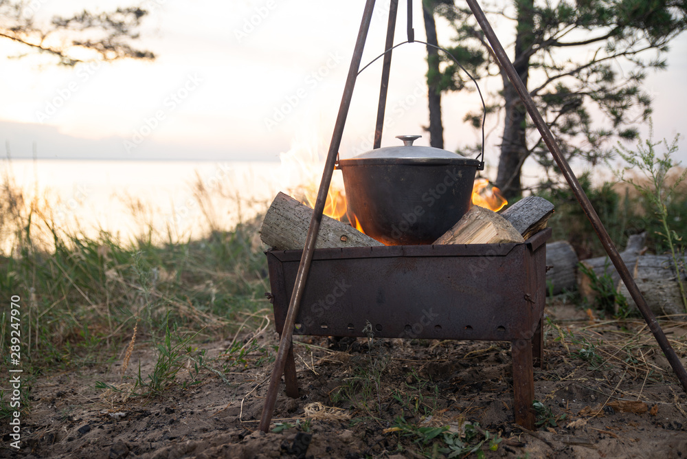 Hiking pot in the bonfire. Traveling in the mountains with tents Hiking pot in the bonfire. Traveling in the mountains with tents