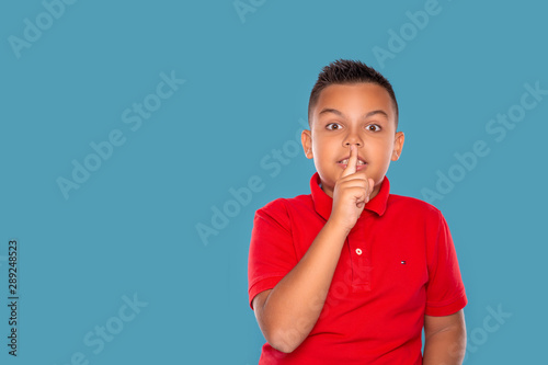 Waist up   emotional portrait of a boy   asking not to tell a secret  isolated on blue background with copy space in studio.