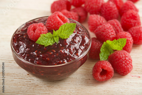 raspberries jam on wooden background © lenkaprusova