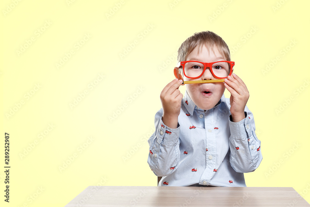 Back to school. Child boy in red glasses sitting at desk with pencil. Pupil of primary school. Back to school. Child boy in red glasses sitting at desk with pencil. Pupil of primary school.