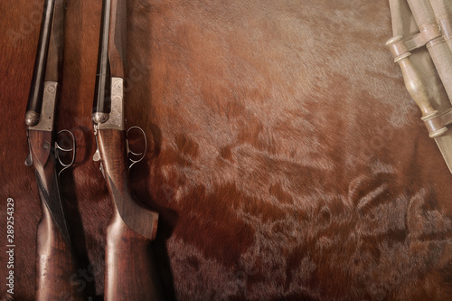 Hunting concept with two shotgun arranged on brown background.