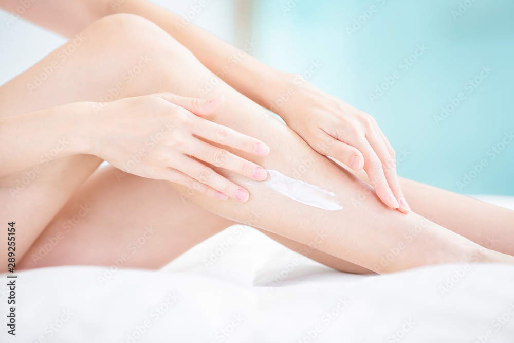 Woman applying cream onto leg