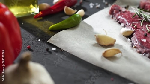 cloves of garlic fall on the table. cheese steak, pepper, olive oil lie on a rough dark surface. delicious food