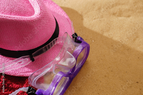 Top view of sandy beach with towel frame and summer accessories. Background with copy space and sand texture.