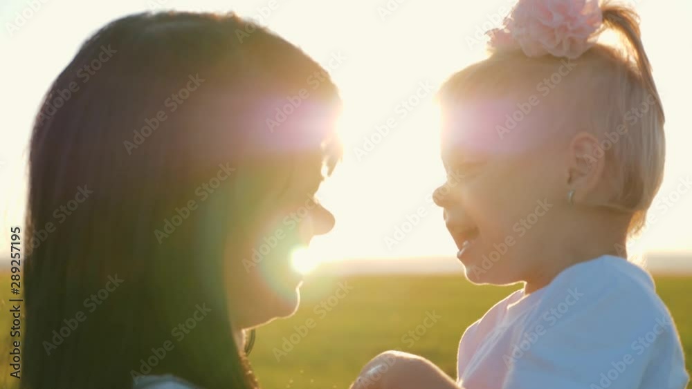 A happy family. Young mother hugs little daughter in a field in the sun at sunset. Tenderness of family relationships. Concept of family love. A happy family. Young mother hugs little daughter in a field in the sun at sunset. Tenderness of family relationships. Concept of family love.
