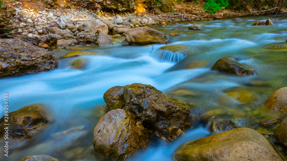 emerald river rushing over the stones in a mountain canyon, long exposure image