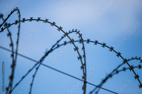 Barbed wire fence around prison walls blue sky in background
