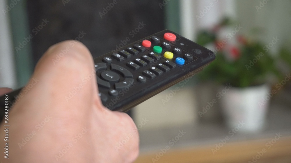In the male hand remote control TV, multimedia. Black color plastic. Multicolored buttons. Close-up. In the male hand remote control TV, multimedia. Black color plastic. Multicolored buttons. Close-up.