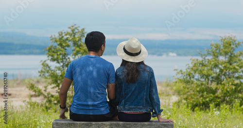 Couple sit together in the park and look at the landscape © leungchopan