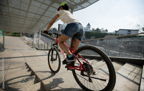 Riding bike down stairs of overpass in city
