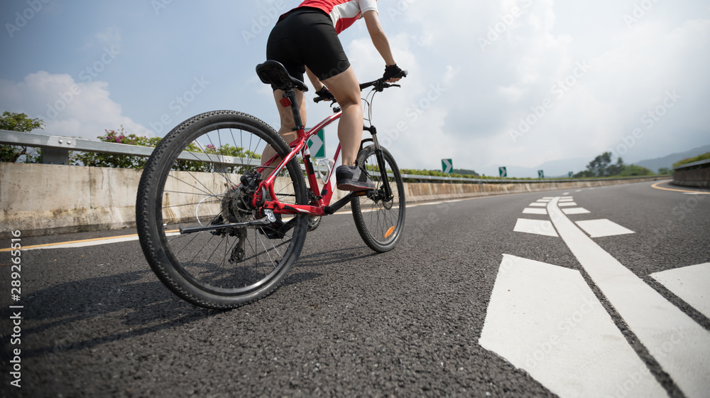 Fototapeta premium Woman cyclist riding Mountain Bike on highway