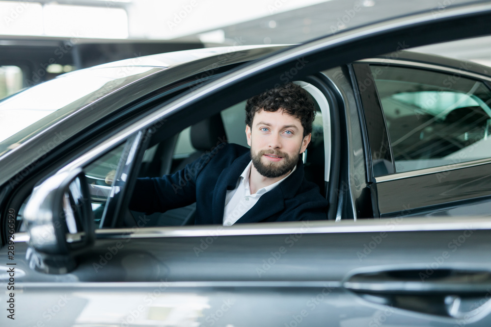 Portrait of a handsome businessman buy new luxury car in the showroom Portrait of a handsome businessman buy new luxury car in the showroom