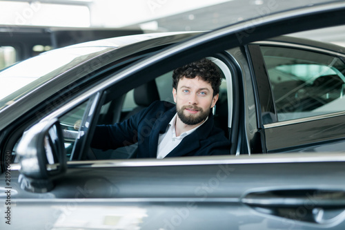 Portrait of a handsome businessman buy new luxury car in the showroom