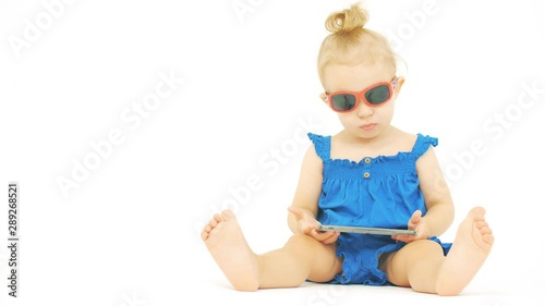 Serious baby wearing sunglasses watches movie or cartoon on a modern smartphone photo