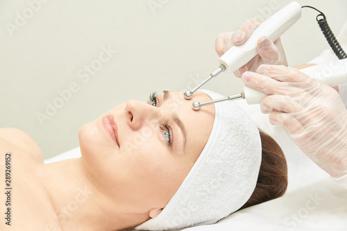 Microcurrent esthetics procedure. Beauty girl face. Cosmetology machine. Doctor hands. Two micro balls. Wrinkle reduction