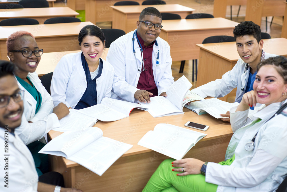 a group of mixed race doctors. Young people smiling while sitting at a table in a hospital office discussing medical topics. a group of mixed race doctors. Young people smiling while sitting at a table in a hospital office discussing medical topics.