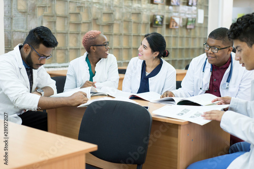 a group of young doctors, mixed race. Sit at the table discussing medical topics.