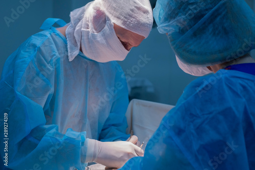 Children's surgeons perform urological surgery. A man and a woman in a mask, and a blue sterile gown, in the operating room.