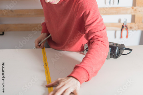 woman with tape measure ready to cut a wood