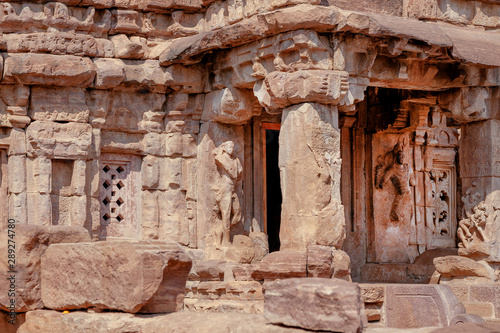Stone columns and textured walls with sculptures of Hindu temple, India. Example of 7th century Indian architecture with reliefs in Pattadakal