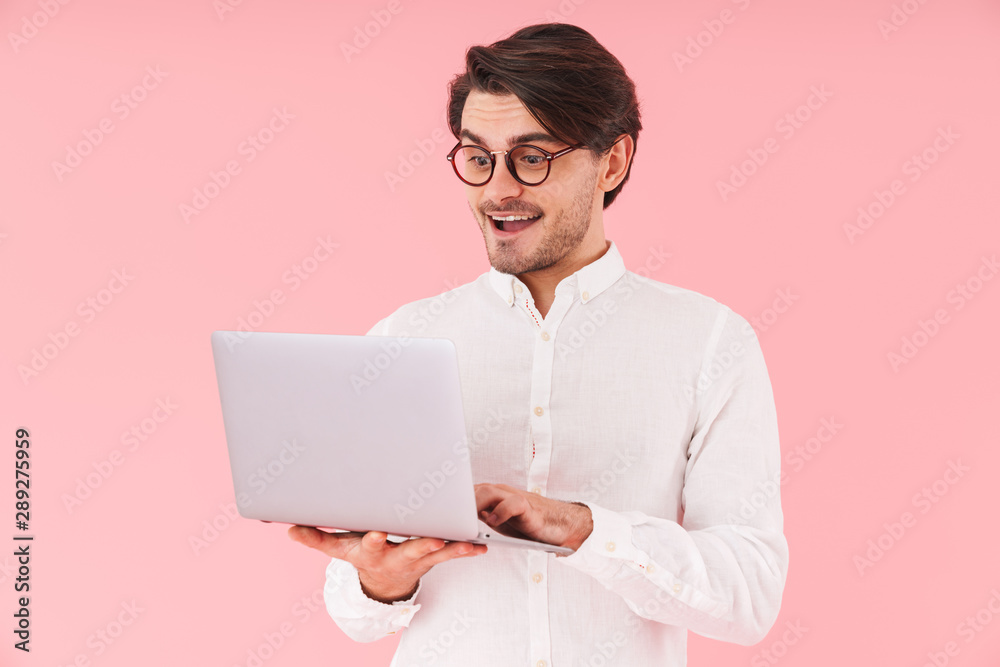 Image of handsome happy man wearing eyeglasses typing on laptop and smiling Image of handsome happy man wearing eyeglasses typing on laptop and smiling