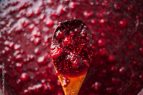 raspberry jam is kept with a wooden spoon, shallow depth of field