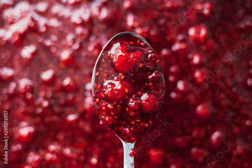 raspberry jam is kept with a metal spoon, shallow depth of field photo