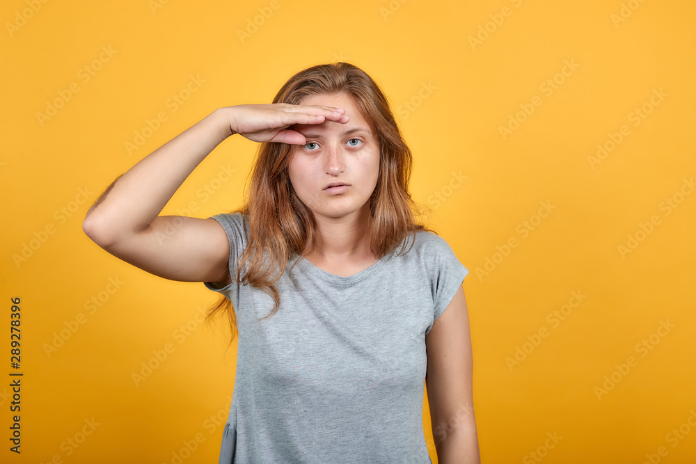 brunette girl in gray t-shirt over isolated orange background shows emotions brunette girl in gray t-shirt over isolated orange background shows emotions