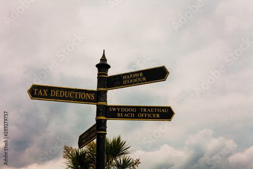 Writing note showing Tax Deductions. Business concept for an amount or cost that subtracted from someone s is income Road sign on the crossroads with blue cloudy sky in the background photo