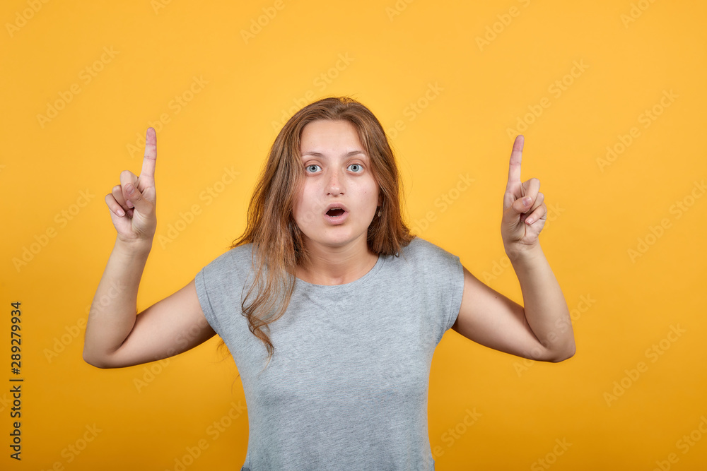 brunette girl in gray t-shirt over isolated orange background shows emotions brunette girl in gray t-shirt over isolated orange background shows emotions