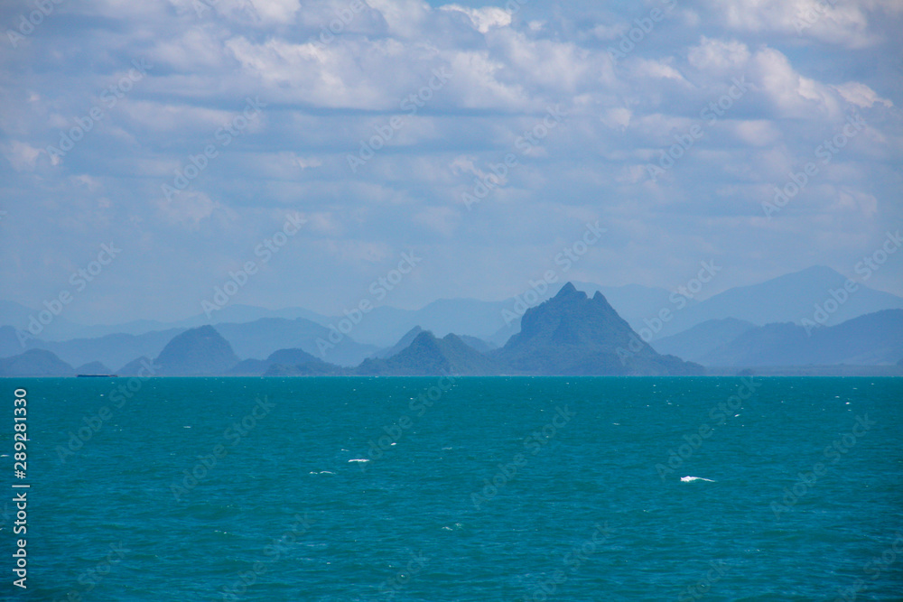 Beautiful sea view on the island, with layers of misty mountains, white clouds, and blue sky.