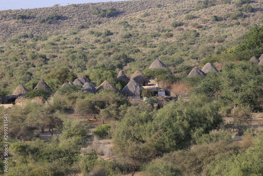 Fototapeta premium Tharparkar Sindh, Pakistan - March, 2019: View of Green Thar Desert Poor hut house, Women Children Colourful Dress, Barren land Drought in Thar Desert