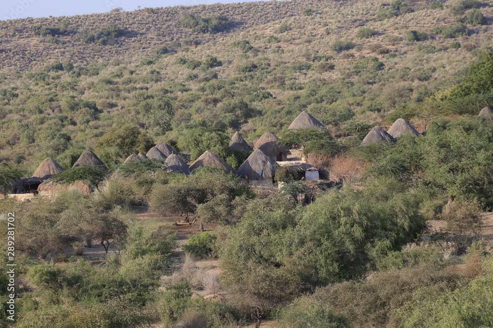 Fototapeta premium Tharparkar Sindh, Pakistan - March, 2019: View of Green Thar Desert Poor hut house, Women Children Colourful Dress, Barren land Drought in Thar Desert