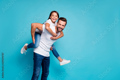 Portrait of cheerful people laughing piggyback wearing white t-shirt denim jeans isolated over blue background photo