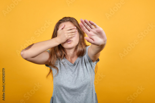 brunette girl in gray t-shirt over isolated orange background shows emotions