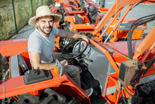 Young agronomist trying tractor for farming, choosing agricultural machinery on the open ground of the shop