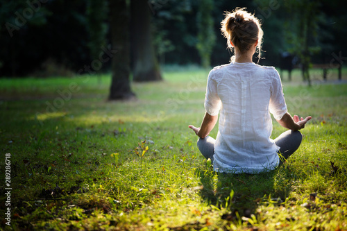 young woman practicing yoga and meditating in the forest