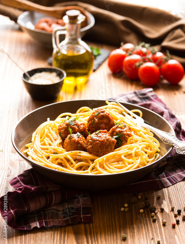 Delicious spaghetti with meatballs in tomato sauce on dark background, italian cuisine