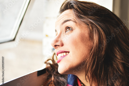 portrait of smiling young woman looking through a window photo