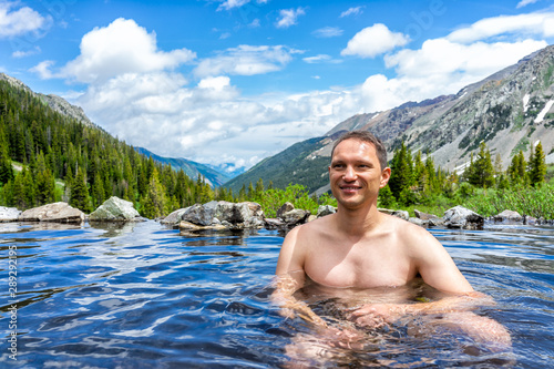 Happy man swimming in hot springs water on Conundrum Creek Trail in Aspen, Colorado in 2019 summer © Kristina Blokhin