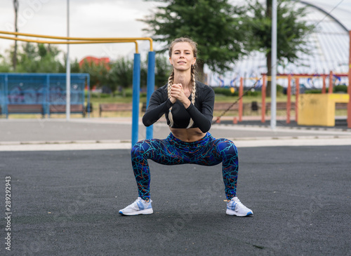 Beautiful athletic girl doing squats on the playground © Павел Костенко