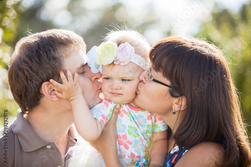 Happy parents kissing their baby on the cheek in the Park