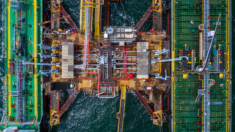 Aerial top view of two fuel tanker ship at the port, Oil terminal is industrial facility for storage of oil and gas petrochemical products ready for transport to further storage facilities.