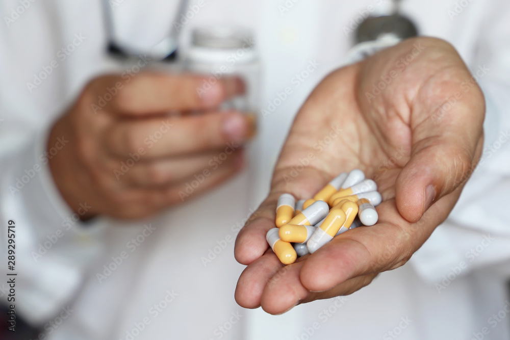 Doctor giving pills, physician holding in palm of hand medication in capsules. Concept of dose of drugs during cold season, vitamins, medical exam, pharmacy, anti-inflammatory Doctor giving pills, physician holding in palm of hand medication in capsules. Concept of dose of drugs during cold season, vitamins, medical exam, pharmacy, anti-inflammatory