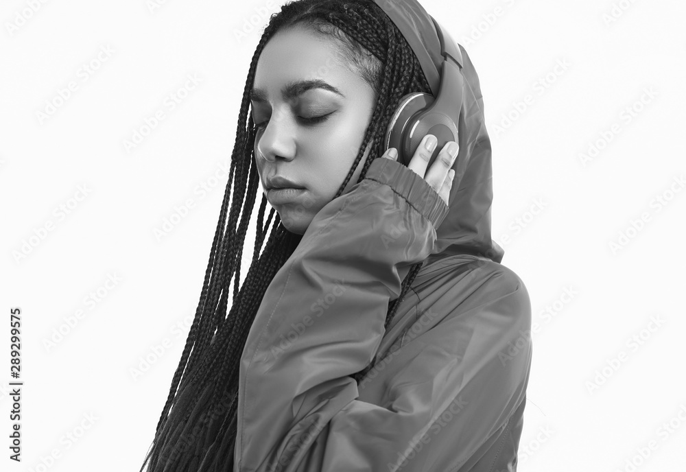 Naklejka premium African teenage girl with dreadlocks in red windbreaker listening music