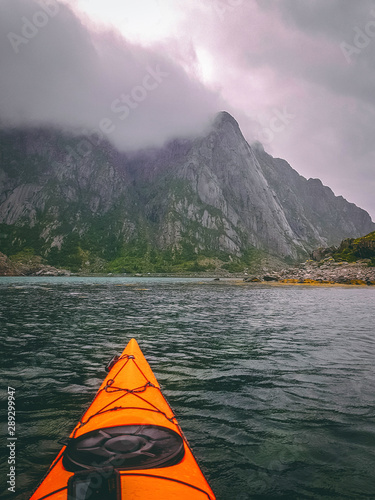Photo of norway with sea, hill, cloudy sky, orange kayak on summer
