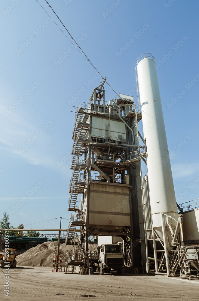 Equipment for production of asphalt, cement and concrete. Concrete plant. High tower of an asphalt plant. Harmful production. A mixture of bitumen and gravel, a mix machine. Equipment for production of asphalt, cement and concrete. Concrete plant. High tower of an asphalt plant. Harmful production. A mixture of bitumen and gravel, a mix machine.